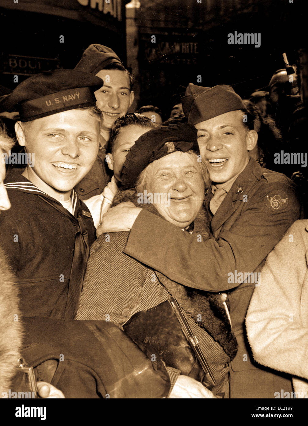 Jubilosos soldado americano abrazos maternal mujer inglesa y victoria sonríe la luz los rostros de los hombres de servicio feliz y civiles en Piccadilly Circus, Londres, celebrando la capitulación incondicional de Alemania. Inglaterra, 7 de mayo de 1945. Pfc. Melvin Weiss. (Ejército) Foto de stock
