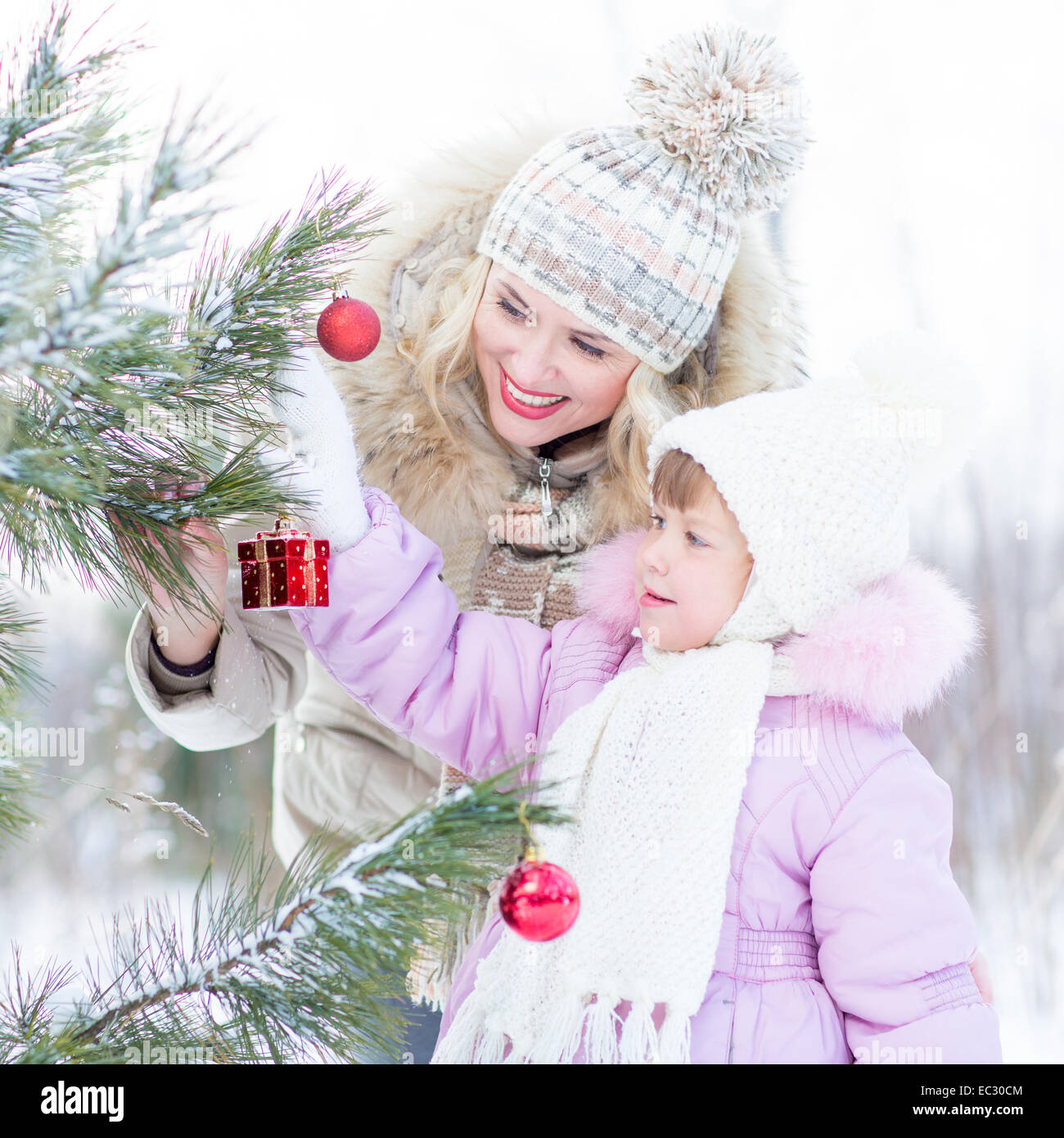 La madre y el niño Feliz Navidad Decora el árbol de invierno al aire libre Foto de stock