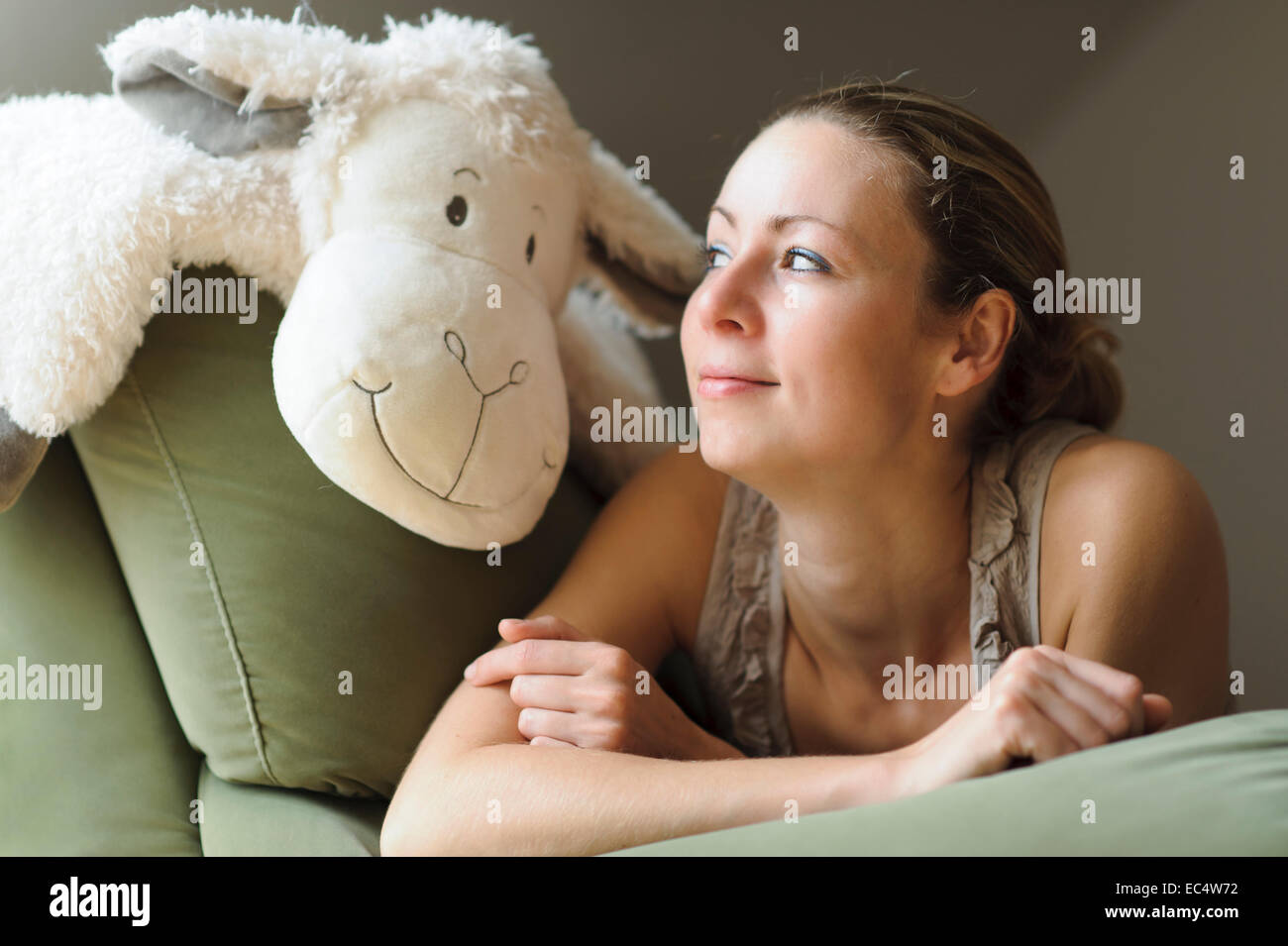 Mujer joven tumbado en la cama con un animal de peluche Foto de stock