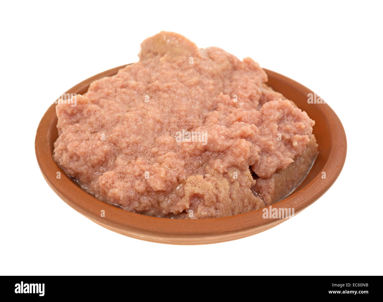 Un pequeño recipiente con una porción de carne en macetas sobre un fondo blanco. Foto de stock