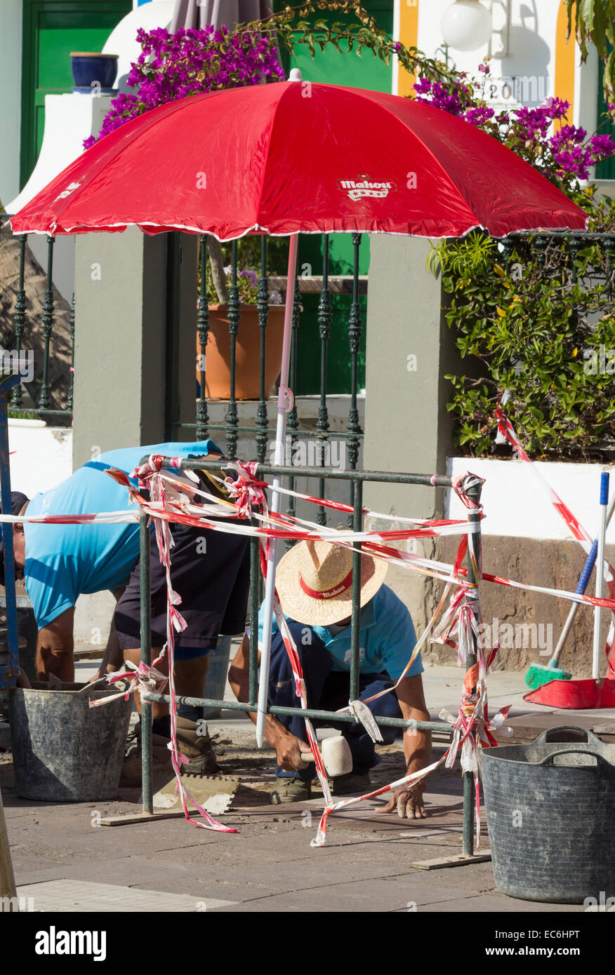 Obreros españoles poniendo adoquines utilizar sombrilla para protegerlos  del sol Fotografía de stock - Alamy
