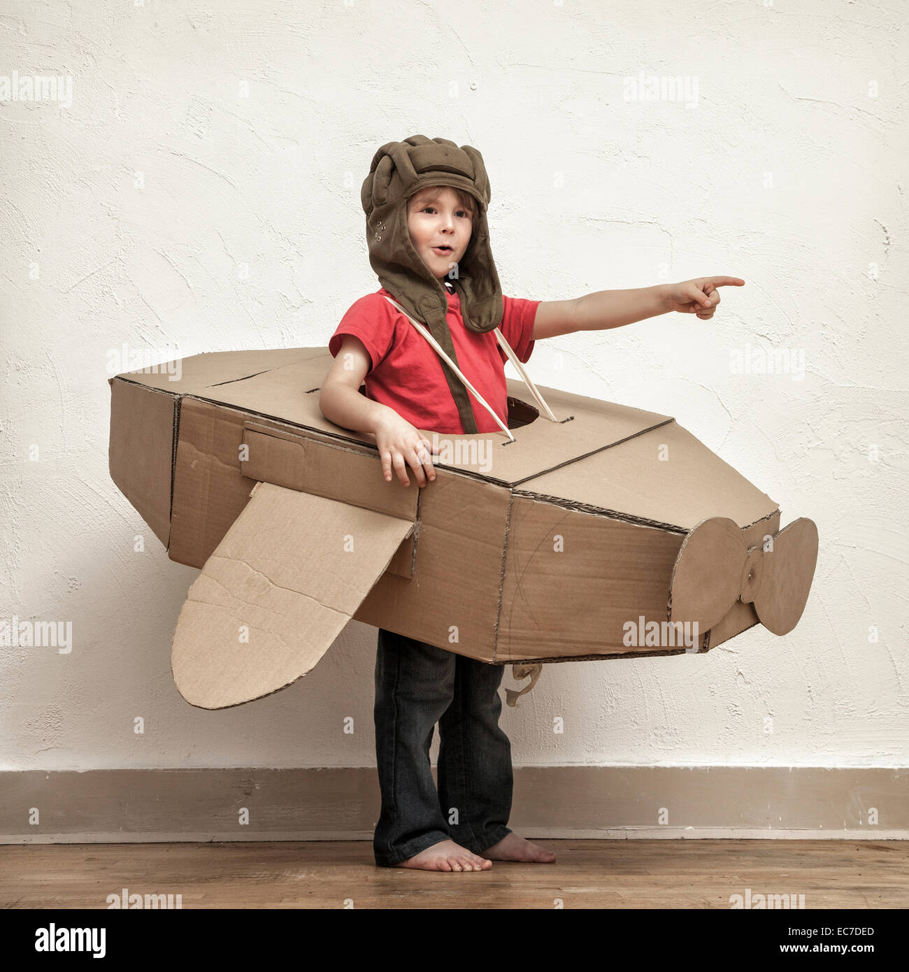 Chico con sombrero de piloto y la caja de cartón avión mostrando en algo  Fotografía de stock - Alamy