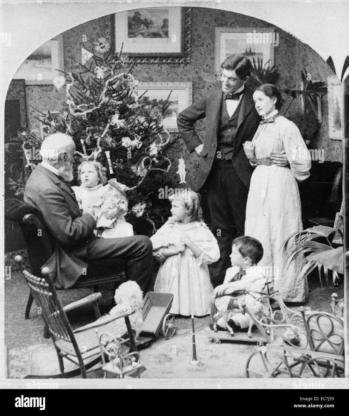 Una familia se sienta con juguetes en frente de un árbol de Navidad durante la visita de mi abuelo en la mañana de Navidad, 1897. En este momento la Navidad habría sido un acontecimiento religioso muy estricto, que habrían sido gastados con familiares cercanos. Foto de stock