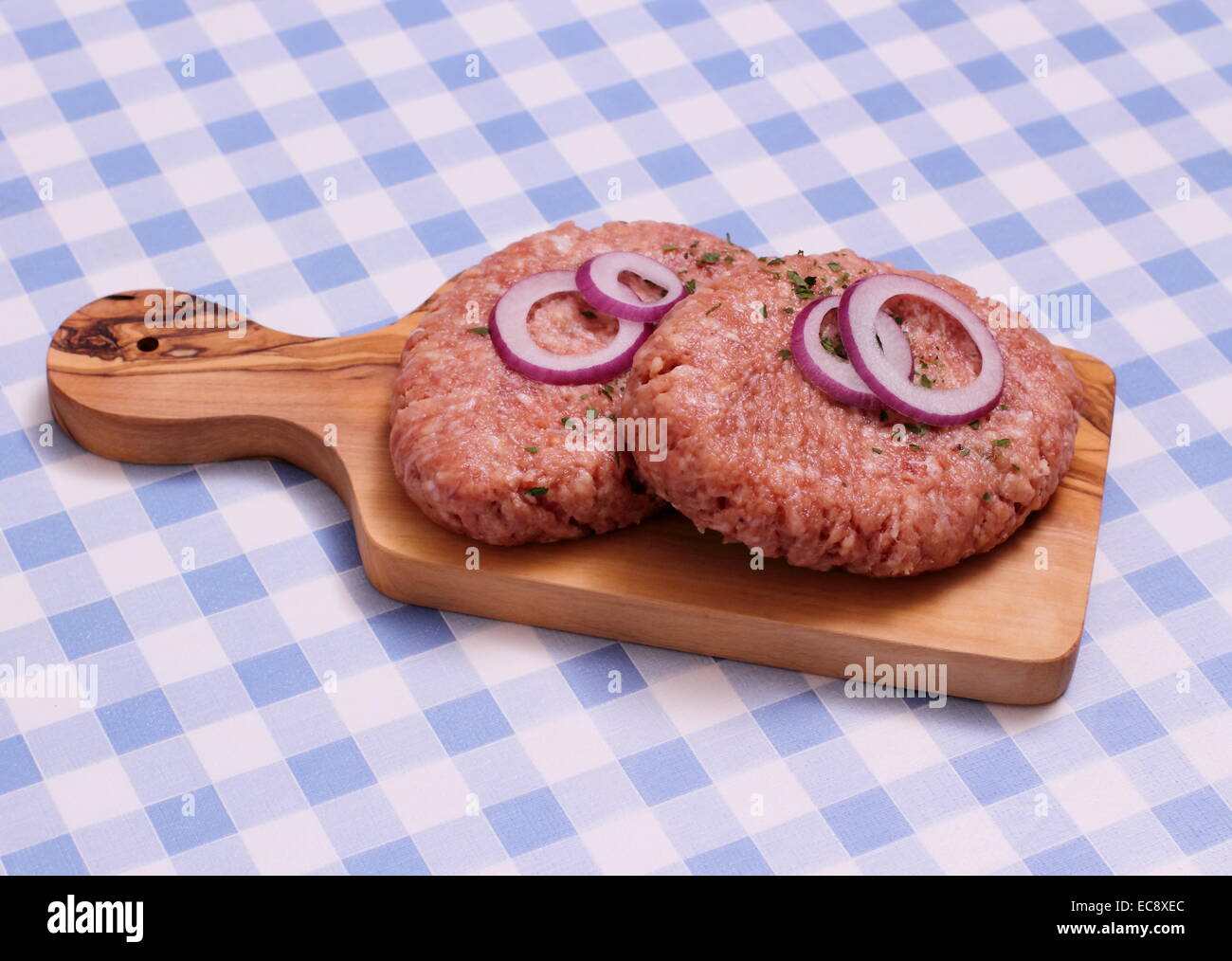 Dos hamburger en la tabla de cortar de madera, blanco y azul a cuadros Foto de stock