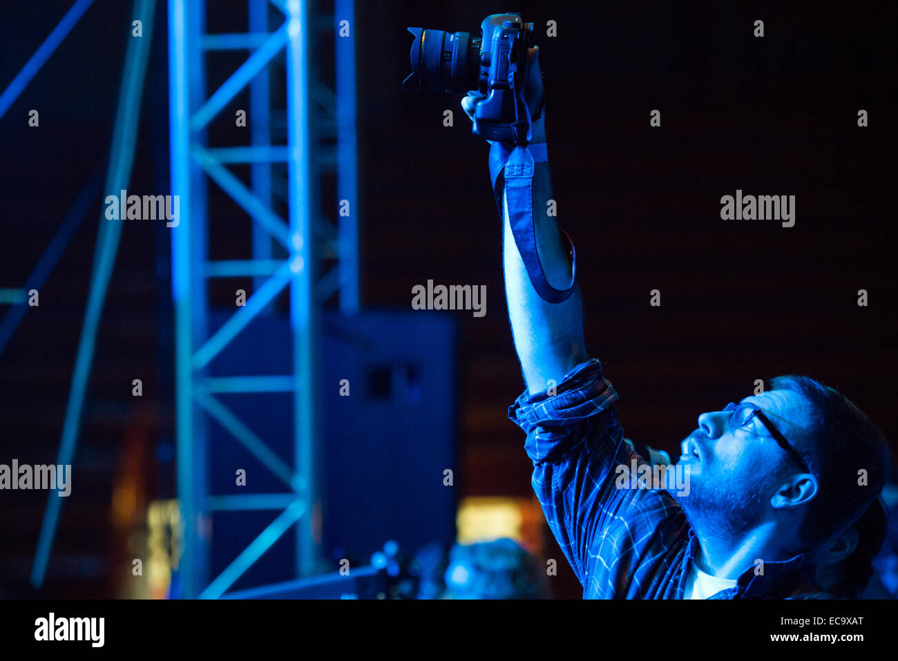 Fotógrafo profesional mantiene su cámara alta en el aire mientras dispara el rendimiento Foto de stock