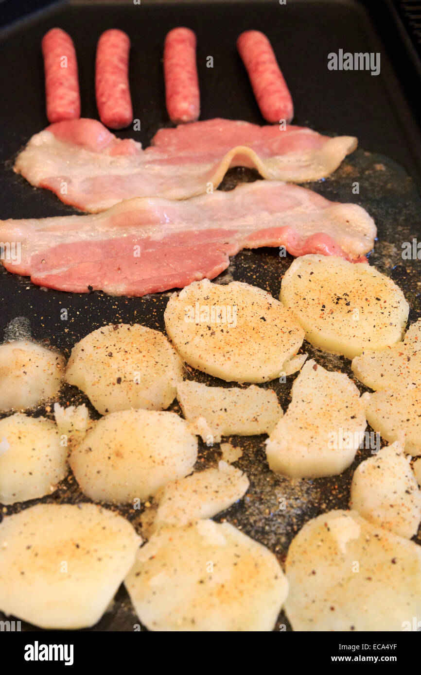 Bacon y salchichas con patatas en una sartén Foto de stock
