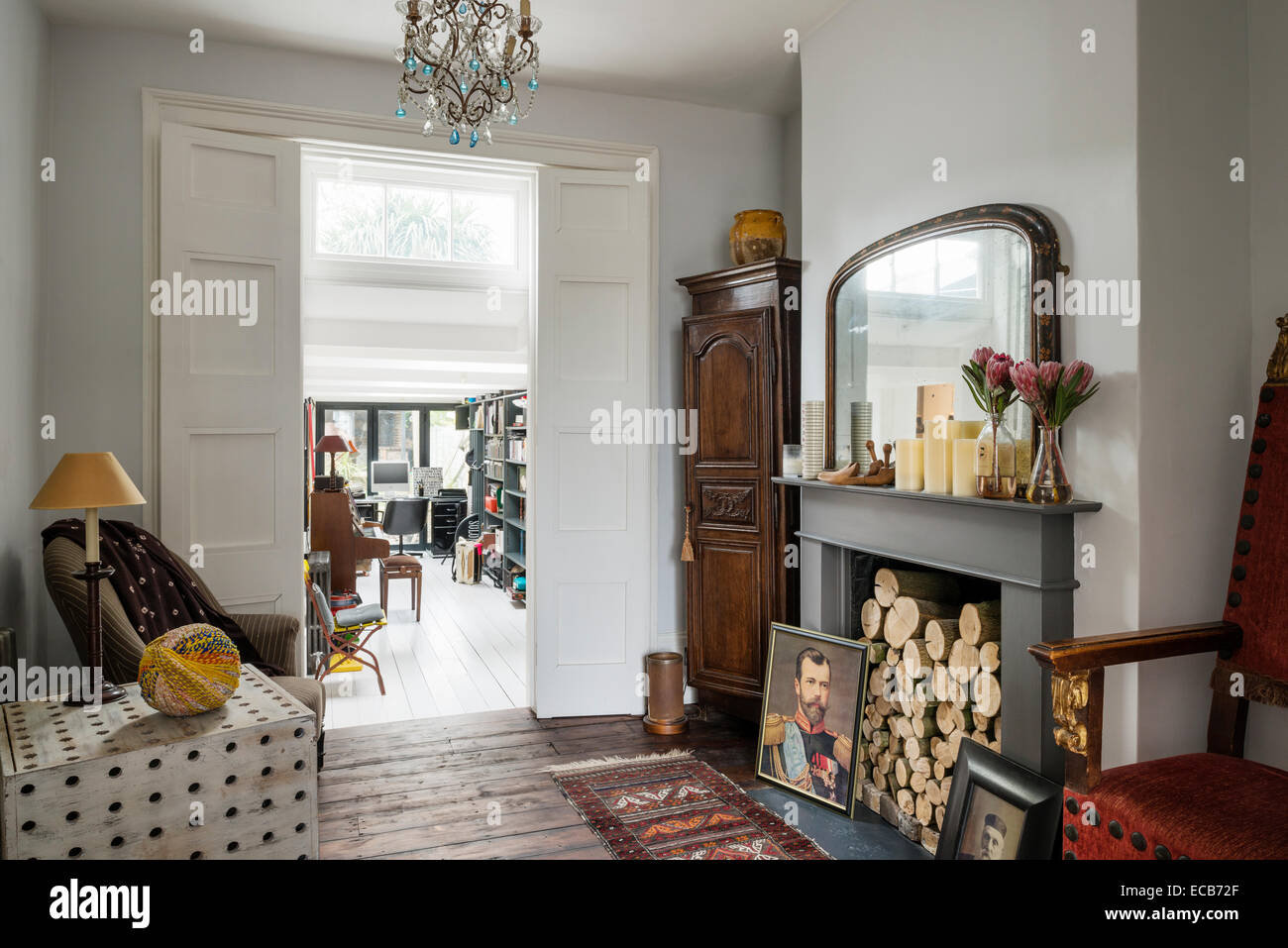 Mesa lateral de madera por Selina van der Geest en living comedor con pisos de madera, chimenea y una lámpara de araña de Anne Fowler en Tetbur Foto de stock