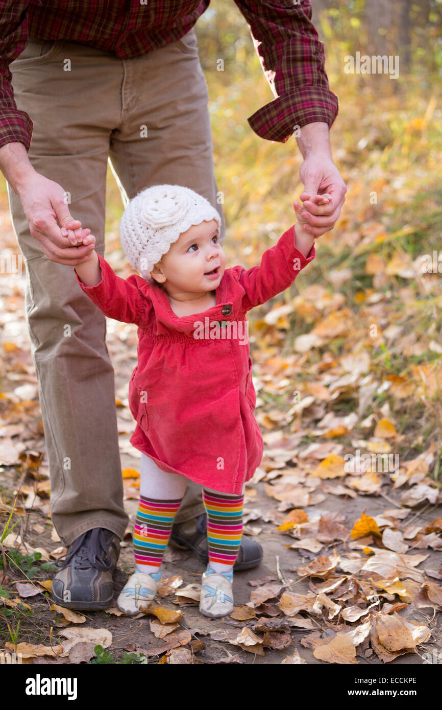 Una niña de un año de edad aprende a caminar con la ayuda de su padre en Kalispell, Montana. Foto de stock