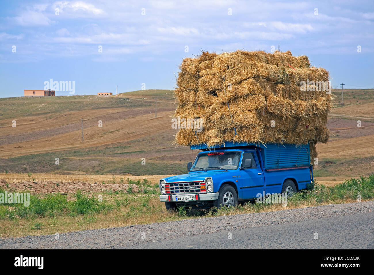 Camioneta azul pesadamente cargado con balas de heno en las zonas rurales de Irán Foto de stock