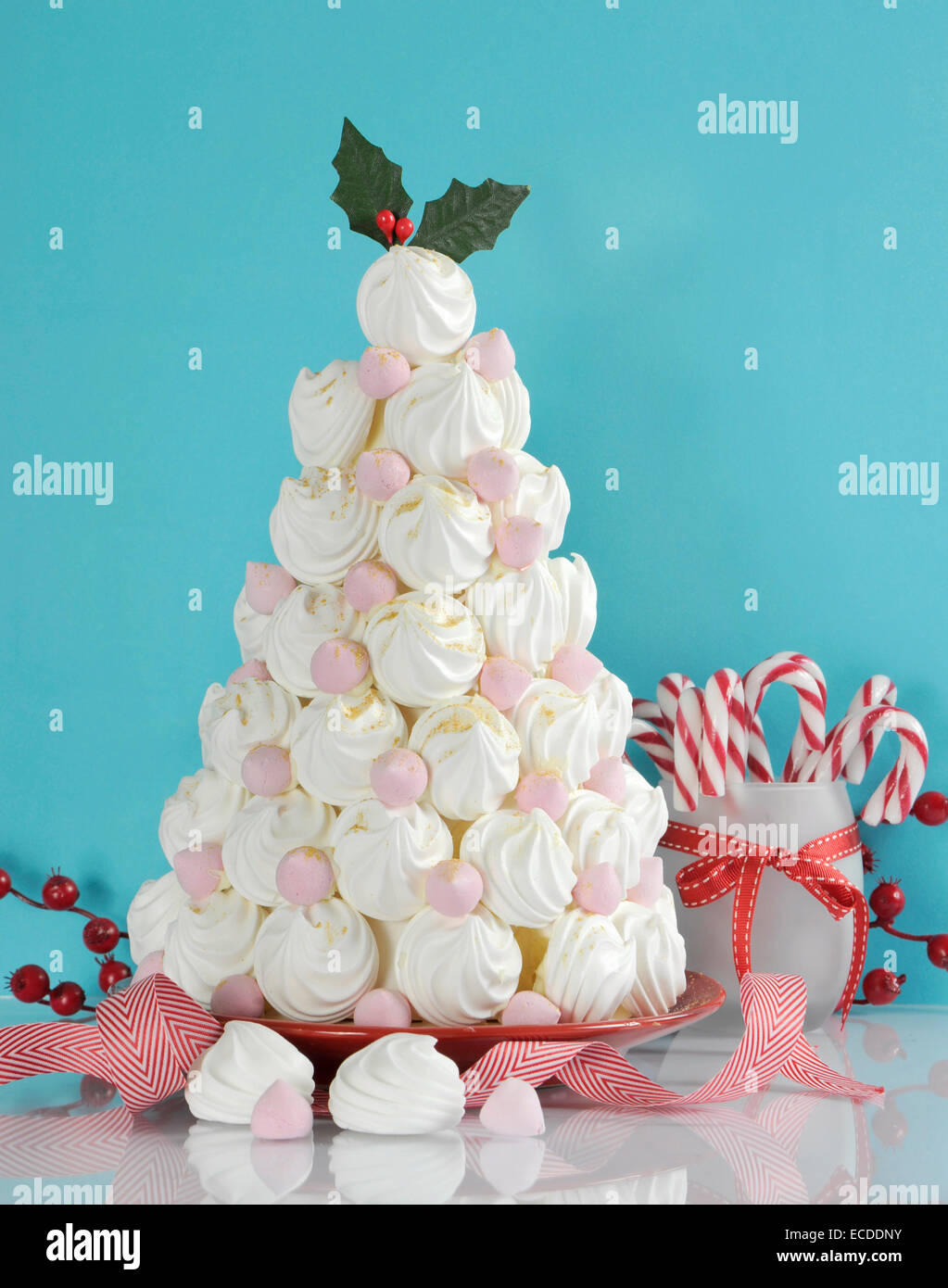 Árbol de Navidad hecho con Dessert Treat merengues rosados y blancos con decoraciones de bastón de caramelo contra un fondo de color azul y blanco. Foto de stock