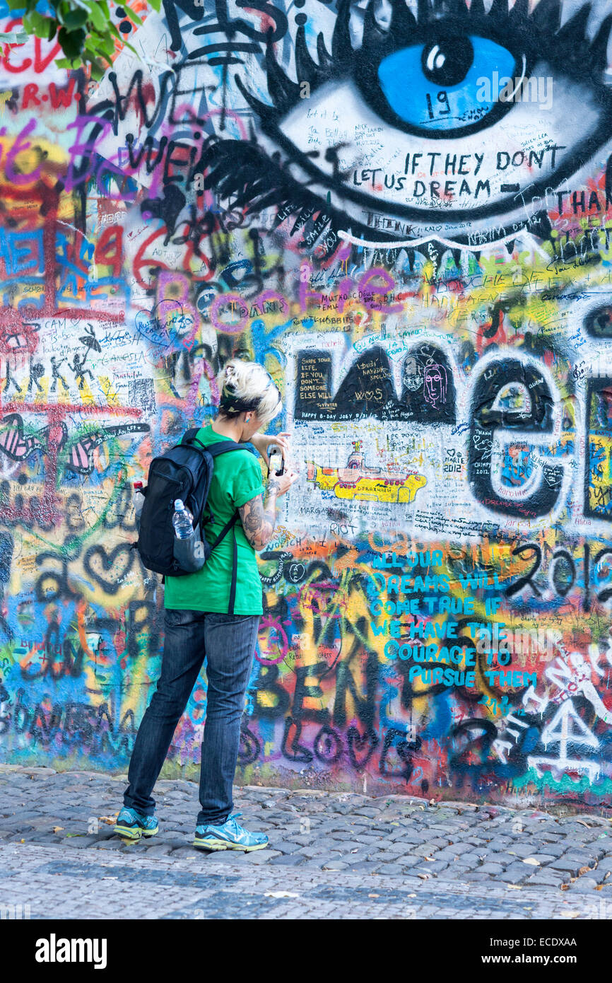 Turista toma una foto con su teléfono del muro John Lennon, Lesser Town, Praga, República Checa Foto de stock