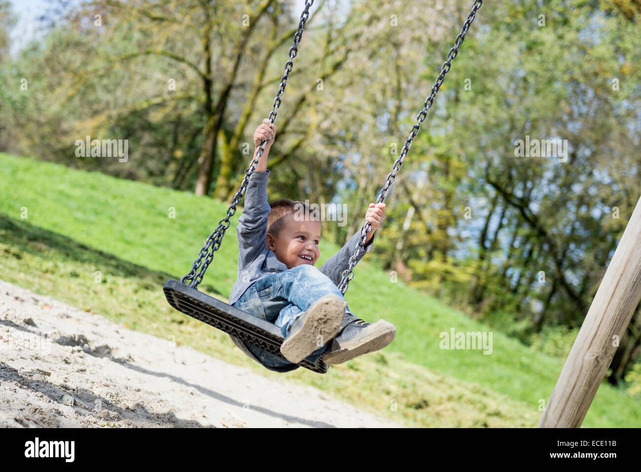 Feliz joven balanceándose en el columpio infantil Foto de stock