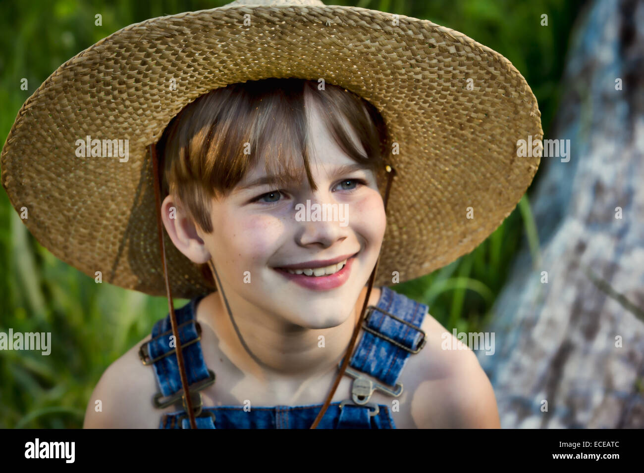 Retrato de un sonriente niño usando un sombrero de paja Foto de stock