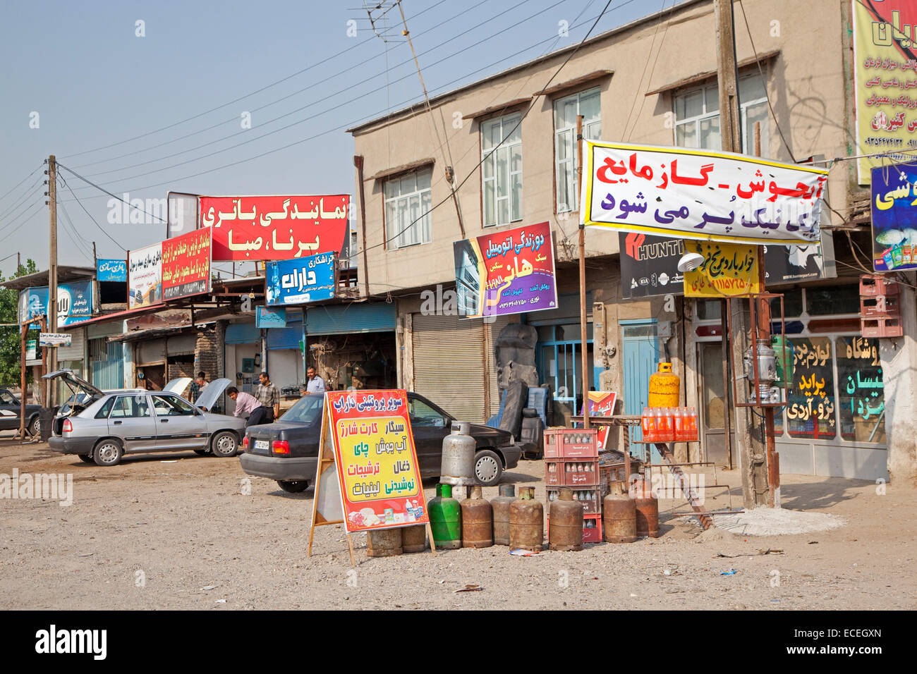 Los iraníes que trabajan en coche en el garage primitivo, talleres de reparación y tienda de comestibles en el pueblo de Irán Foto de stock