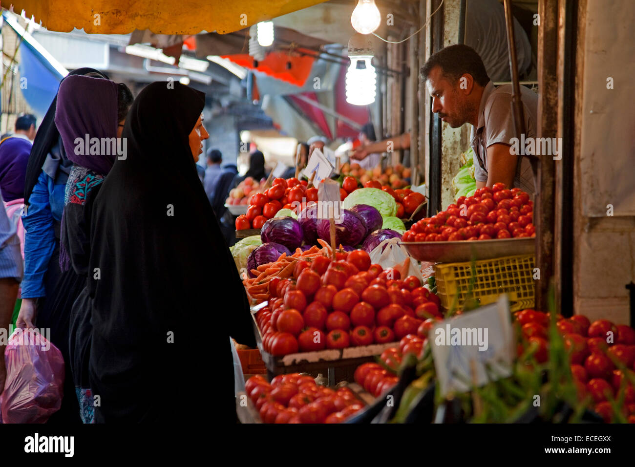 La mujer musulmana iraní usando pañuelos comprando verduras y tomates rojos en el mercado alimenticio stand en Gorgan / Gurgan, Golestán, Irán Foto de stock