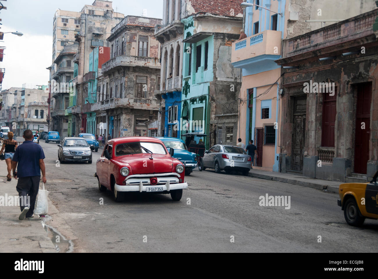 Los edificios ruinosos y vintage coches americanos usados como taxis son un espectáculo común en el distrito central de La Habana. Foto de stock