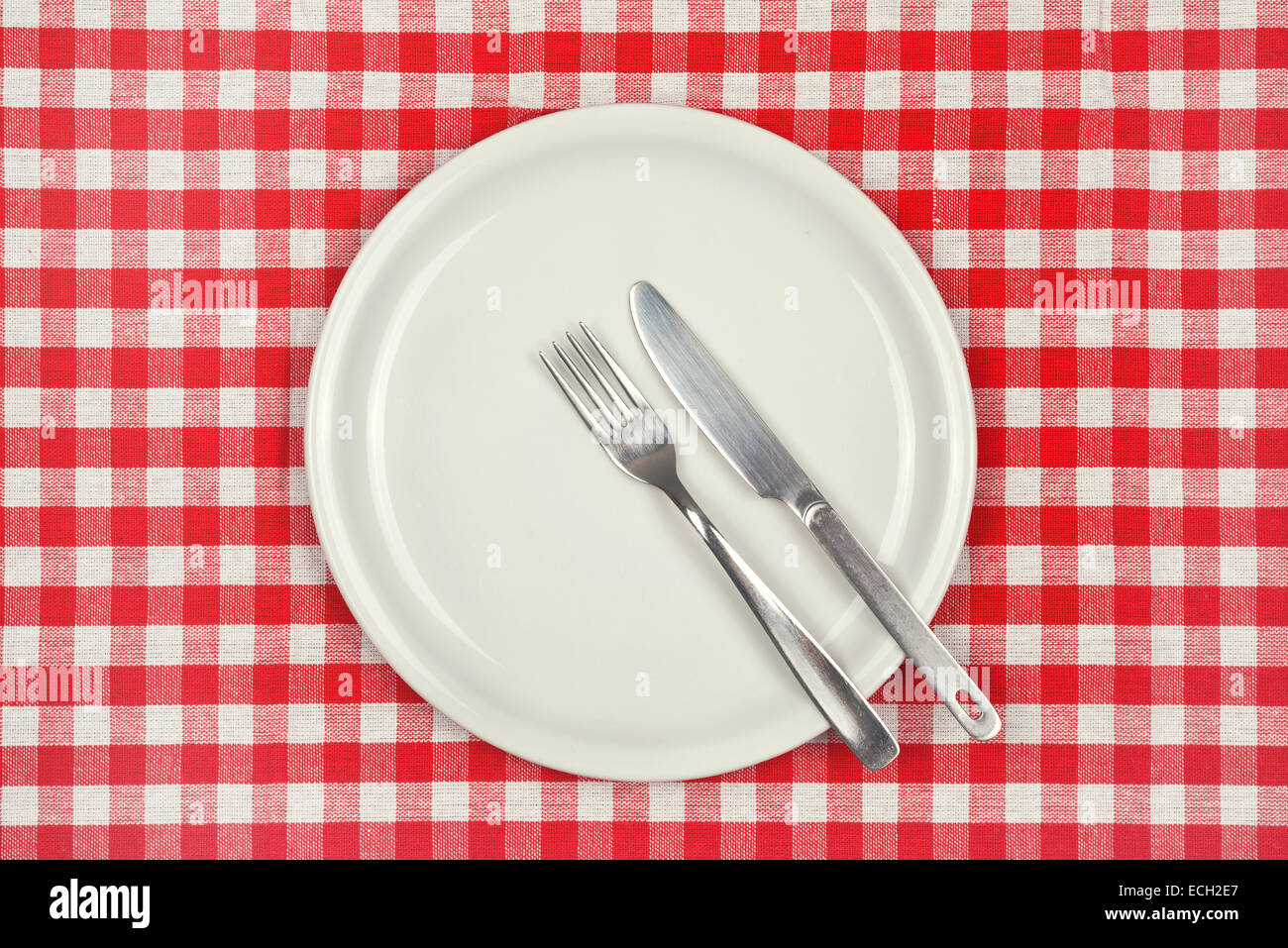 Placa de vacío en la mesa de restaurante con manteles a cuadros rojos y blancos Foto de stock