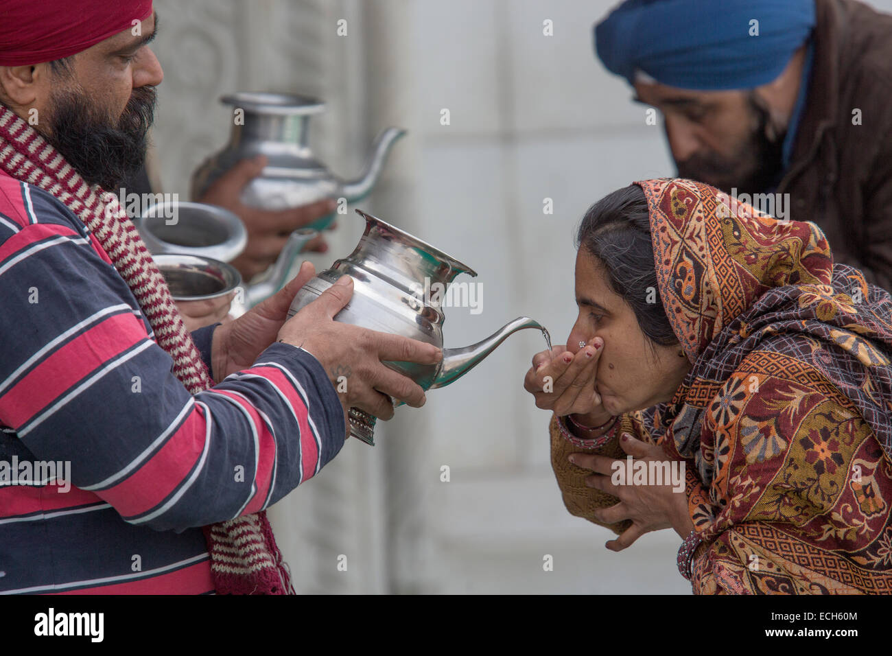 Los peregrinos beber agua bendita, Gurudwara Bangla Sahib, El Templo Sikh, Delhi, India Foto de stock