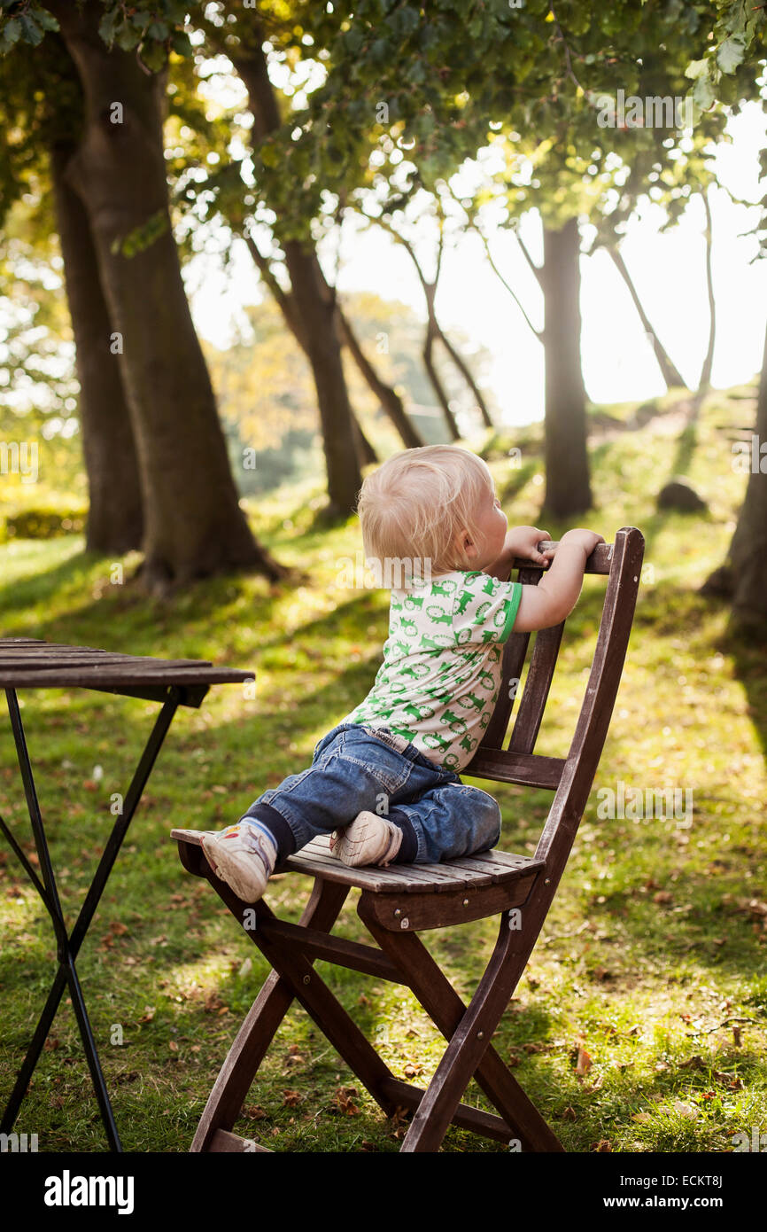 La longitud completa de Baby Boy sentado en la silla de madera en el parque  Fotografía de stock - Alamy
