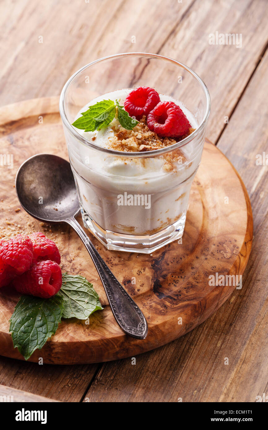 Vaso de delicioso muesli yogur con frambuesas sobre fondo de madera Foto de stock