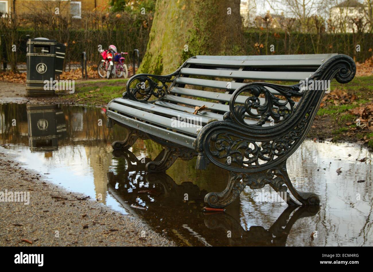 Bench rodeado por un charco en Regent's Park en Londres, Inglaterra Foto de stock
