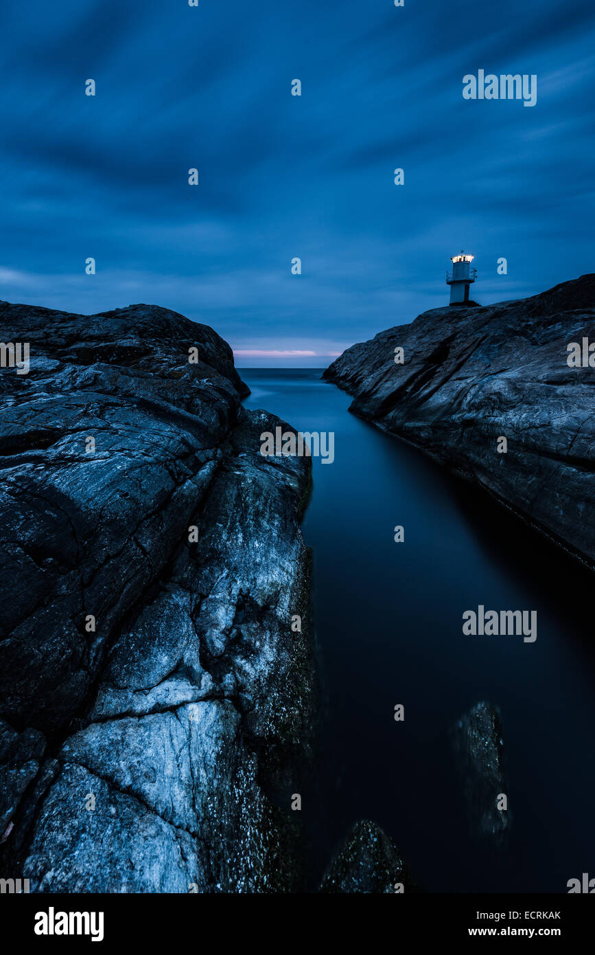 Faro y una orilla rocosa en la noche Foto de stock