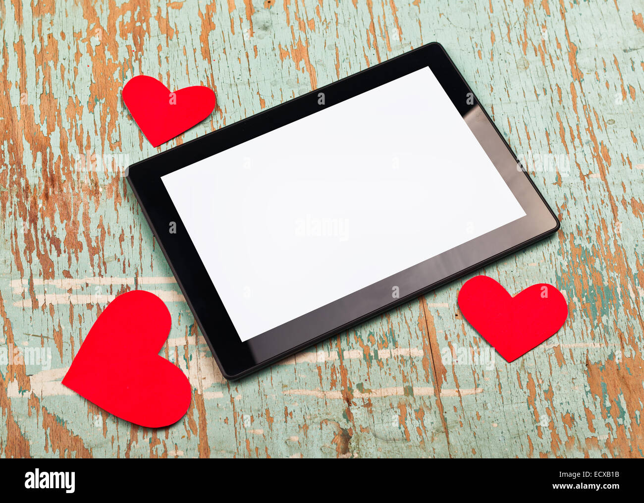 El Día de San Valentín de espacio de copia en digital tablet PC con pantalla en blanco y rojo corazones de papel viejo grunge textura de madera. Foto de stock