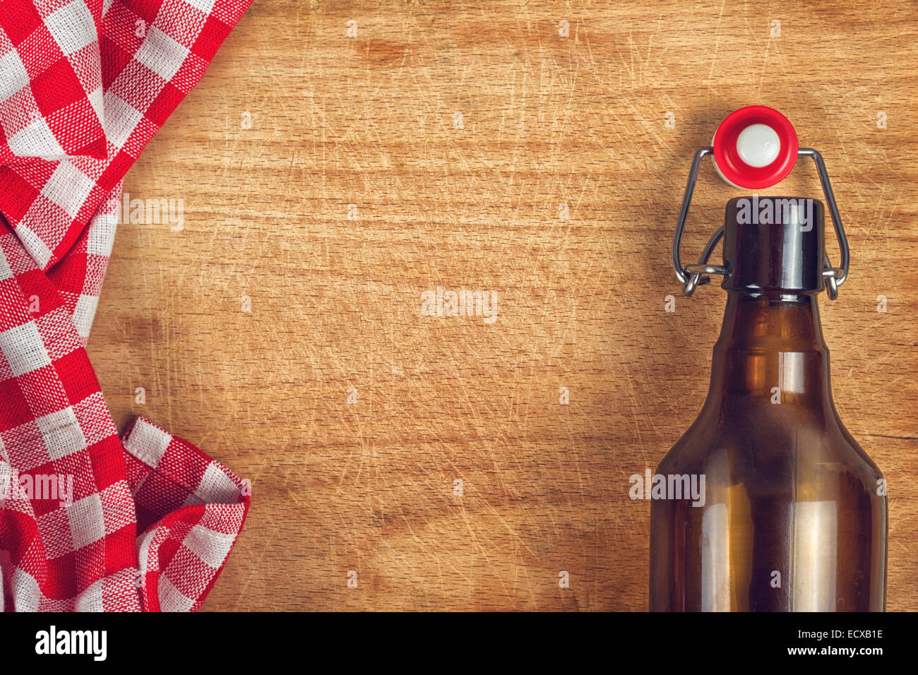 Botellas de cerveza vacías con Swing Flip Top Stopper sobre mesa de madera con manteles a cuadros rojos y blancos y copie el espacio Foto de stock