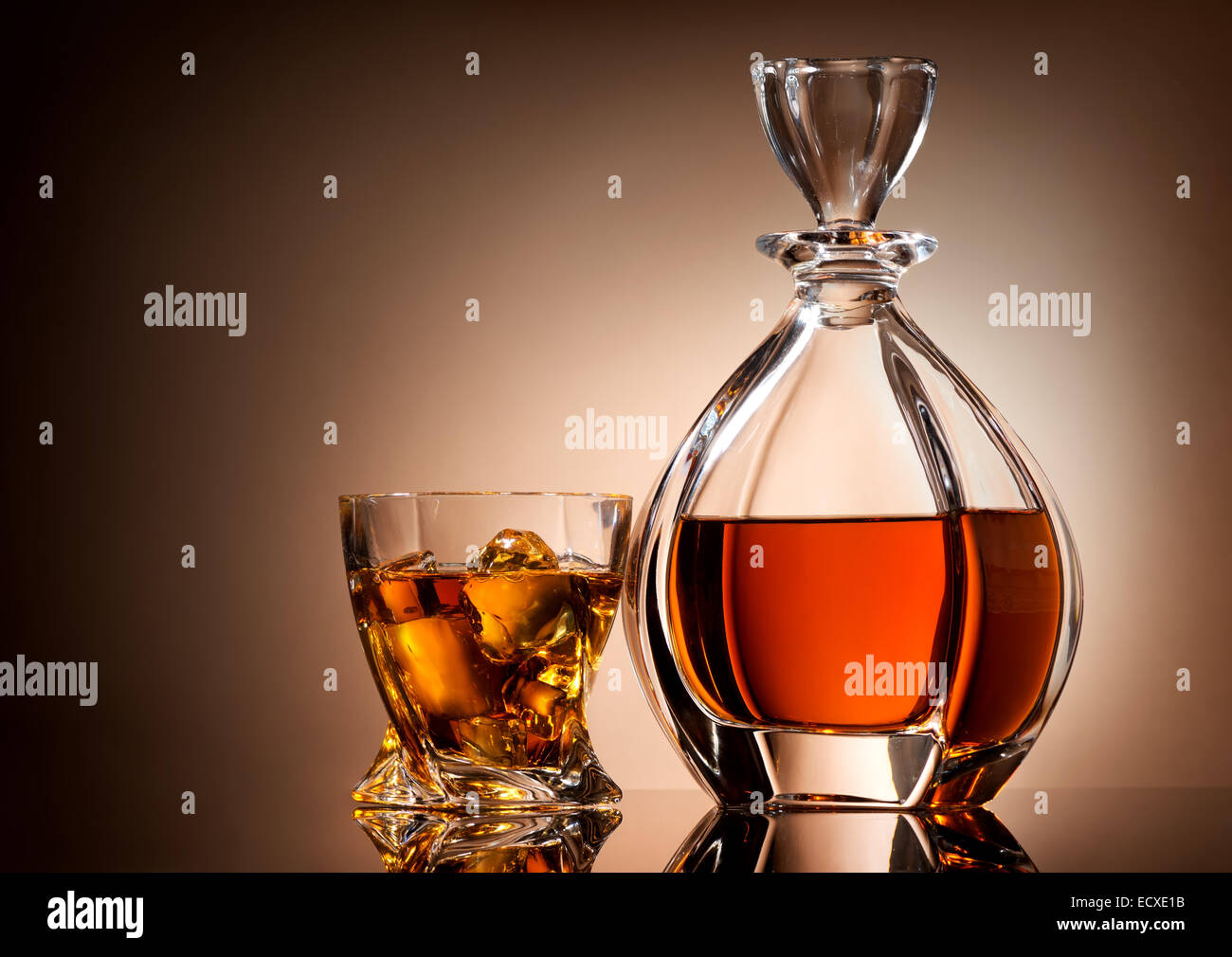 Decantador y vaso de whisky de oro sobre fondo marrón Foto de stock
