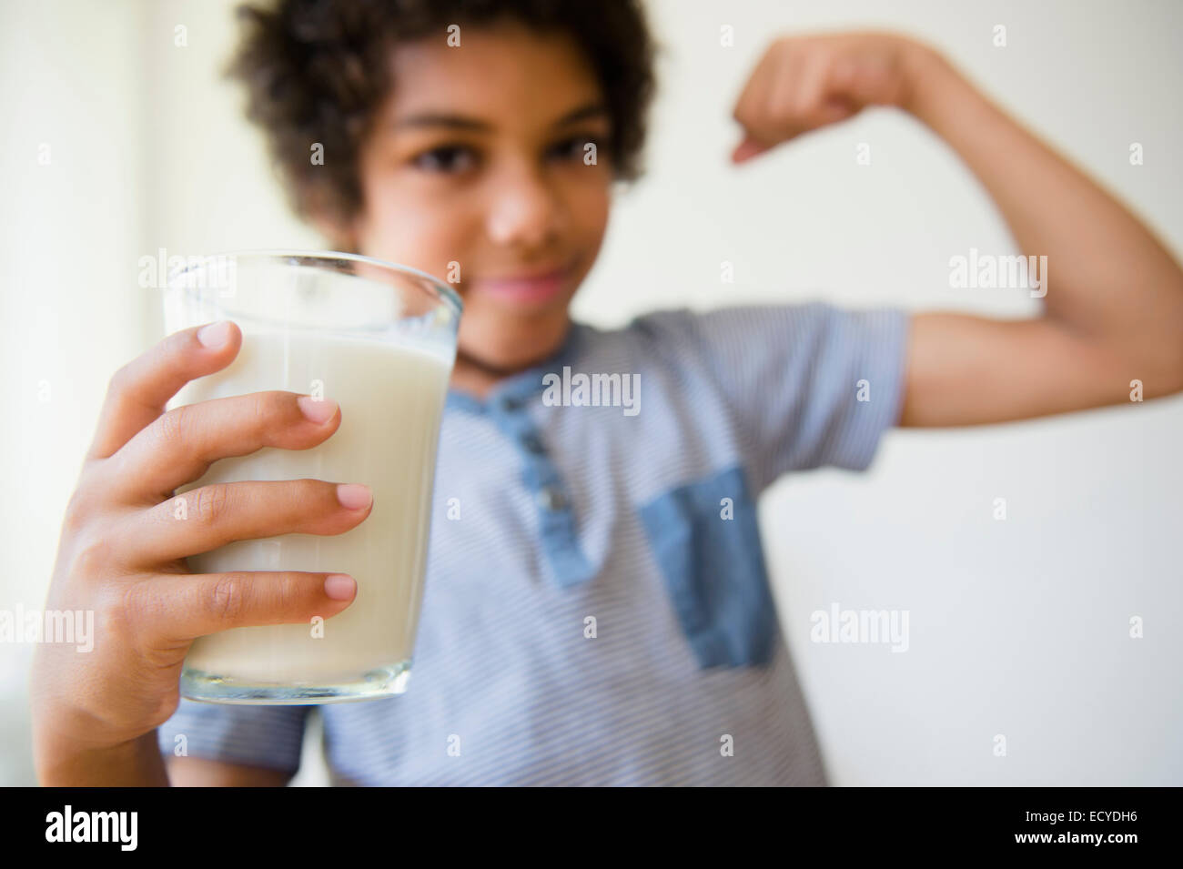 Mestizos boy flexionando sus músculos y beber un vaso de leche Foto de stock