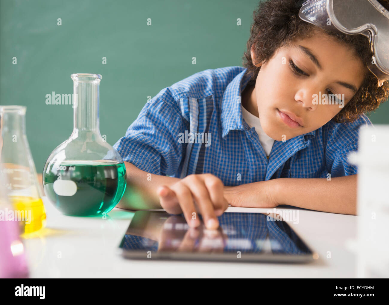 Mestizos boy utilizando tablet digital del laboratorio de ciencias en el aula Foto de stock