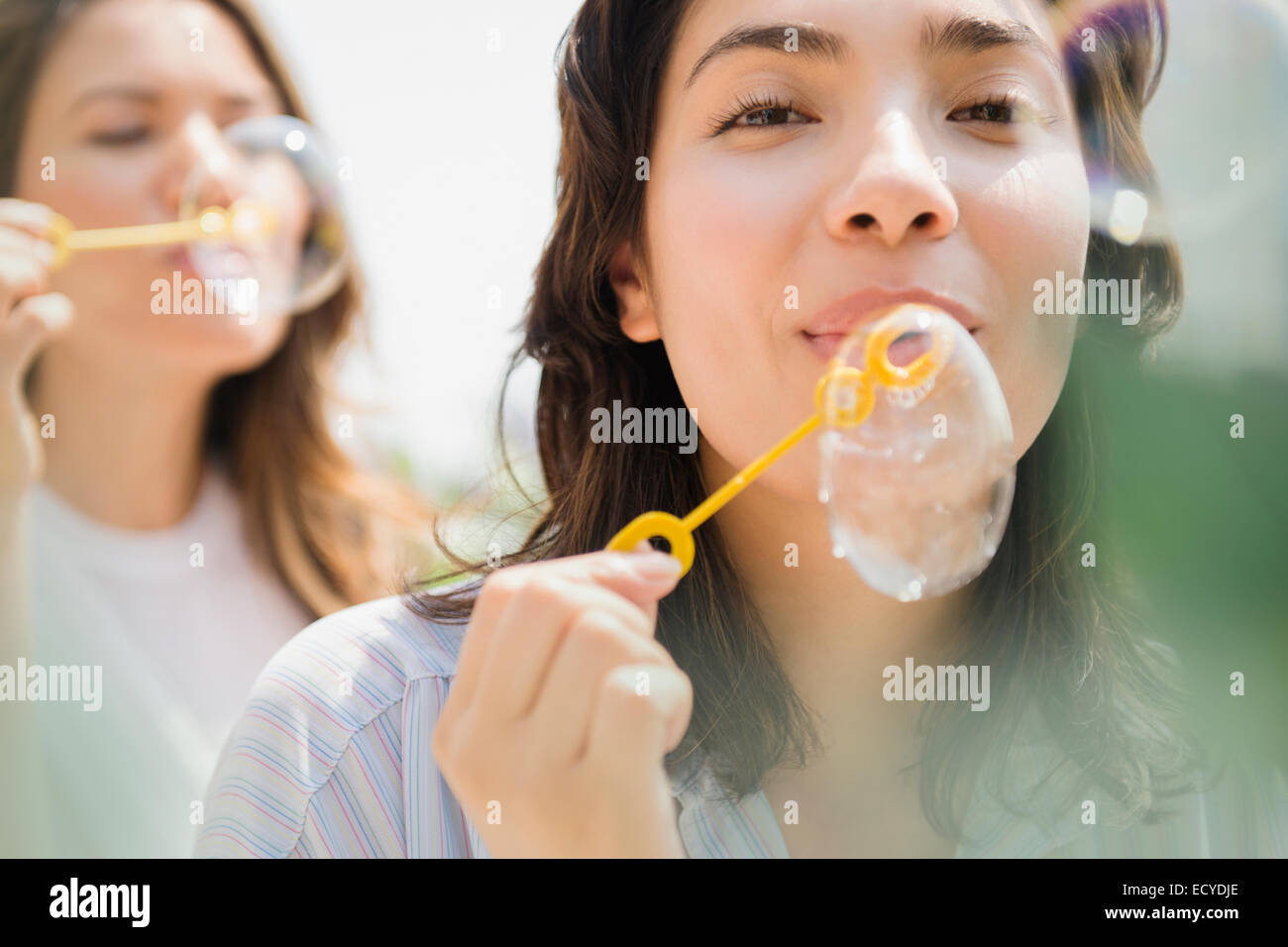 Las mujeres hispanas soplando burbujas al aire libre Foto de stock