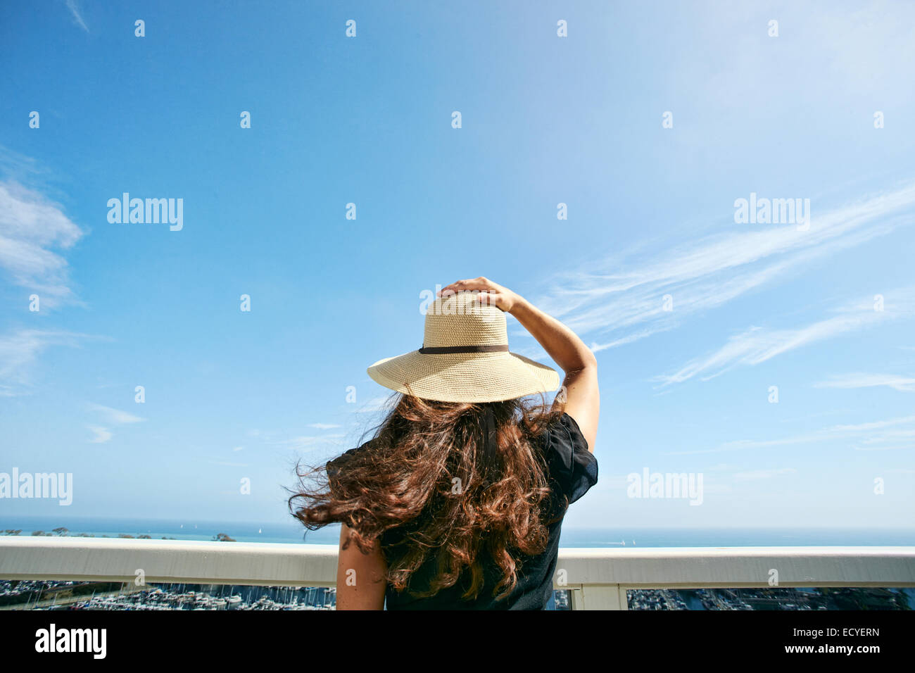 Mujer con sombrero para el sol, admirando vistas panorámicas desde el balcón Foto de stock