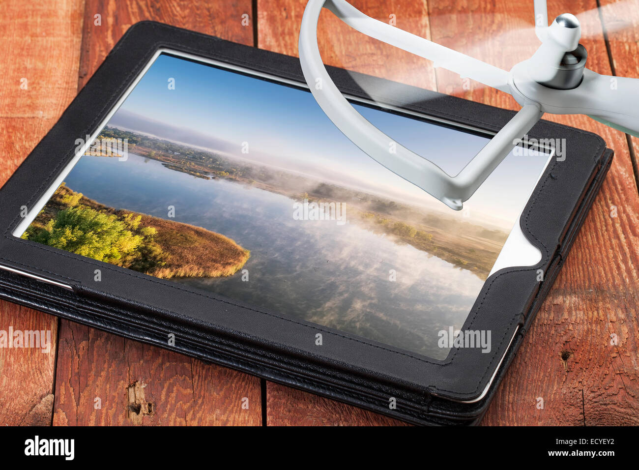Concepto de fotografía aérea drone - Revisión de fotos aéreas de un lago brumoso en una tableta digital con un rotor de drone Foto de stock