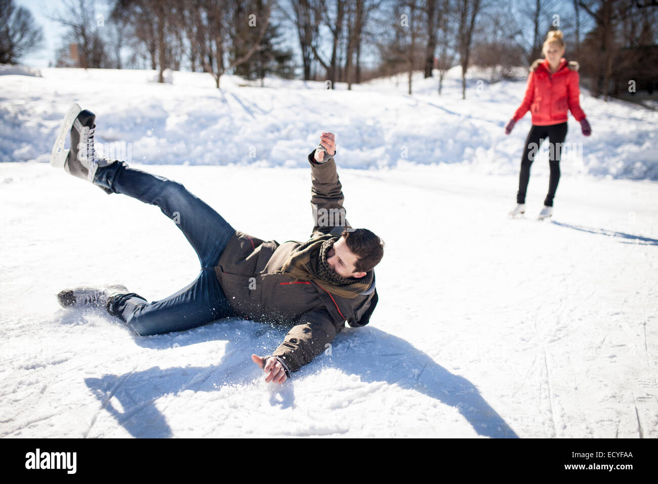 Hombre caucásico cayendo mientras que el patinaje sobre hielo en el lago congelado Foto de stock