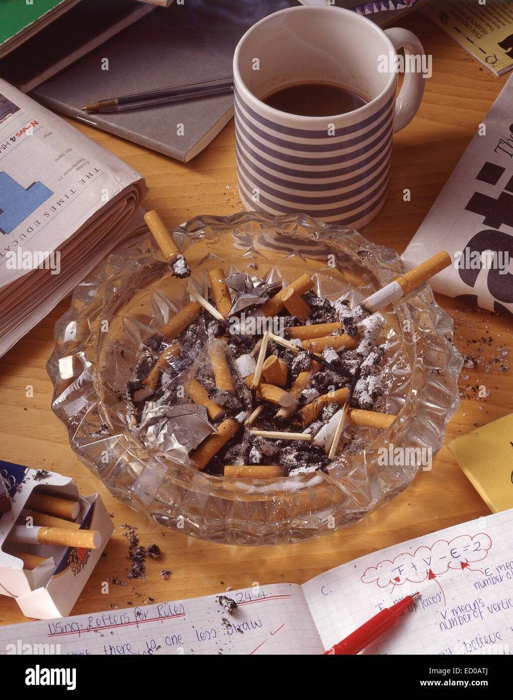 Escritorio de trabajo mostrando el cenicero lleno de colillas de cigarrillos Foto de stock