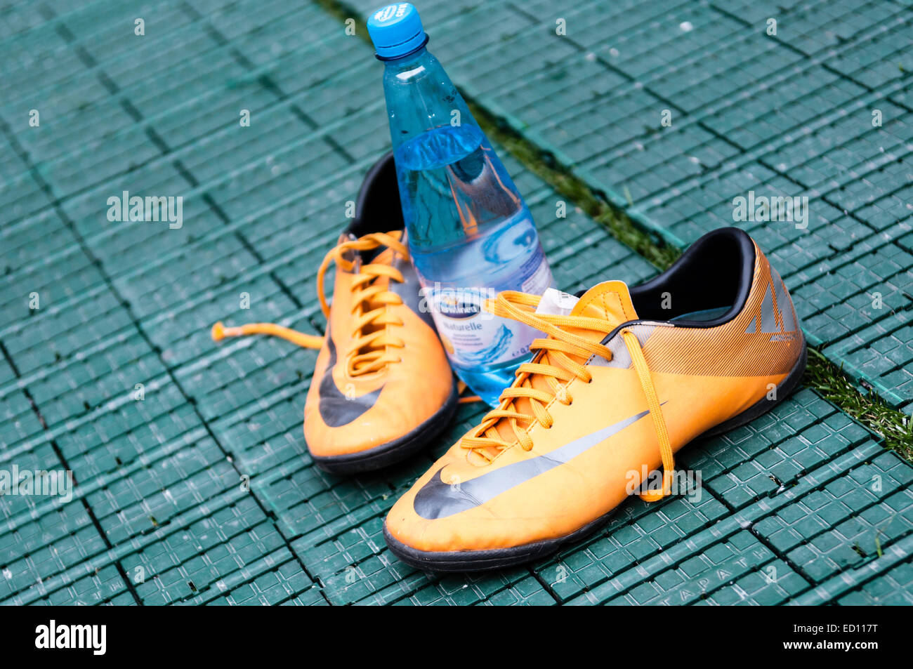 Un par de zapatillas Nike de color naranja y una botella de agua en la  tierra verde oscuro Fotografía de stock - Alamy