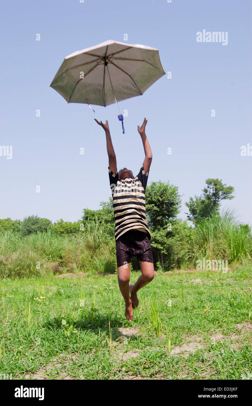 1 niño rural granja boy Saltar sosteniendo paraguas lluvia disfrutar Foto de stock