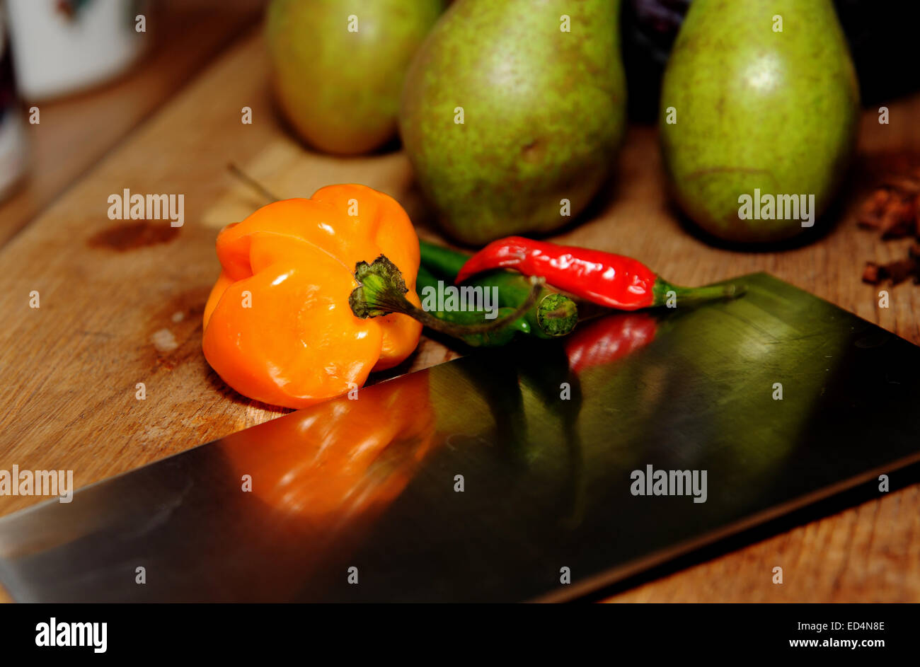 Varios chiles con afilado cuchillo de cocina estilo cleaver sobre una tabla de cortar Foto de stock