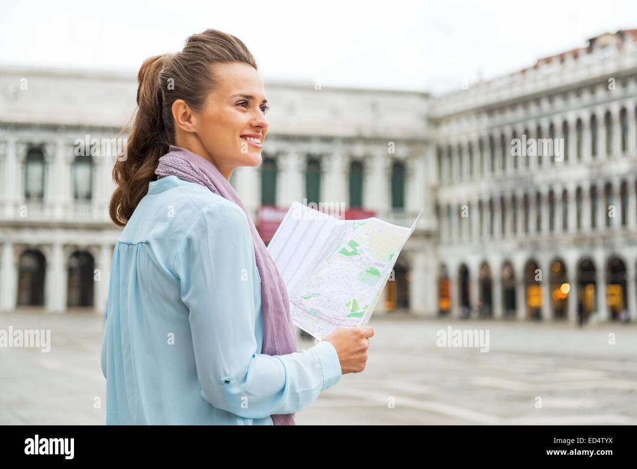 Mujer joven feliz con el mapa en la plaza de San Marcos en Venecia, Italia Foto de stock