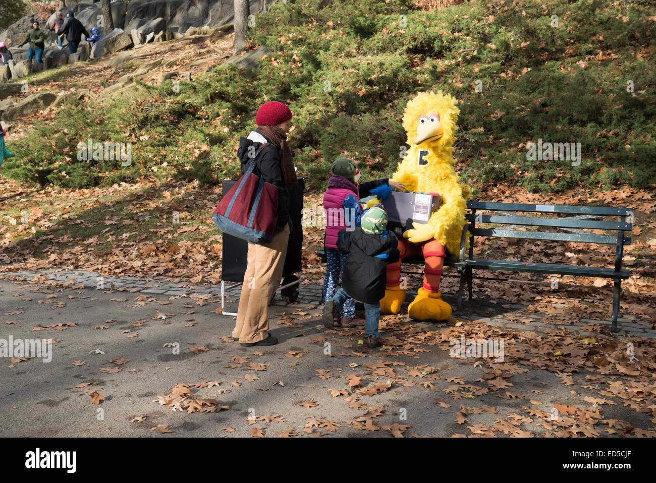 Los niños encuentran Big Bird sentado en un banco en Central Park, New York. Pero hablar con él cuesta $5.00 Foto de stock