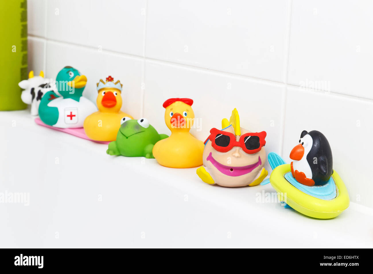 Patitos de goma y otros juguetes por el lado de la bañera Foto de stock