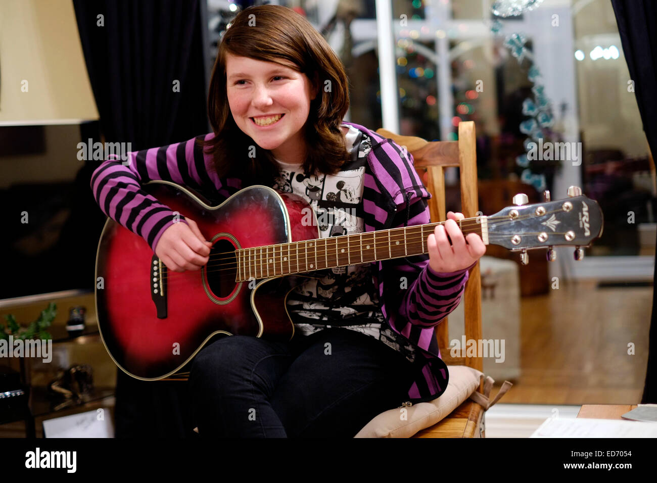 Niña de doce años tocando la guitarra para su familia en el tiempo de Navidad Foto de stock