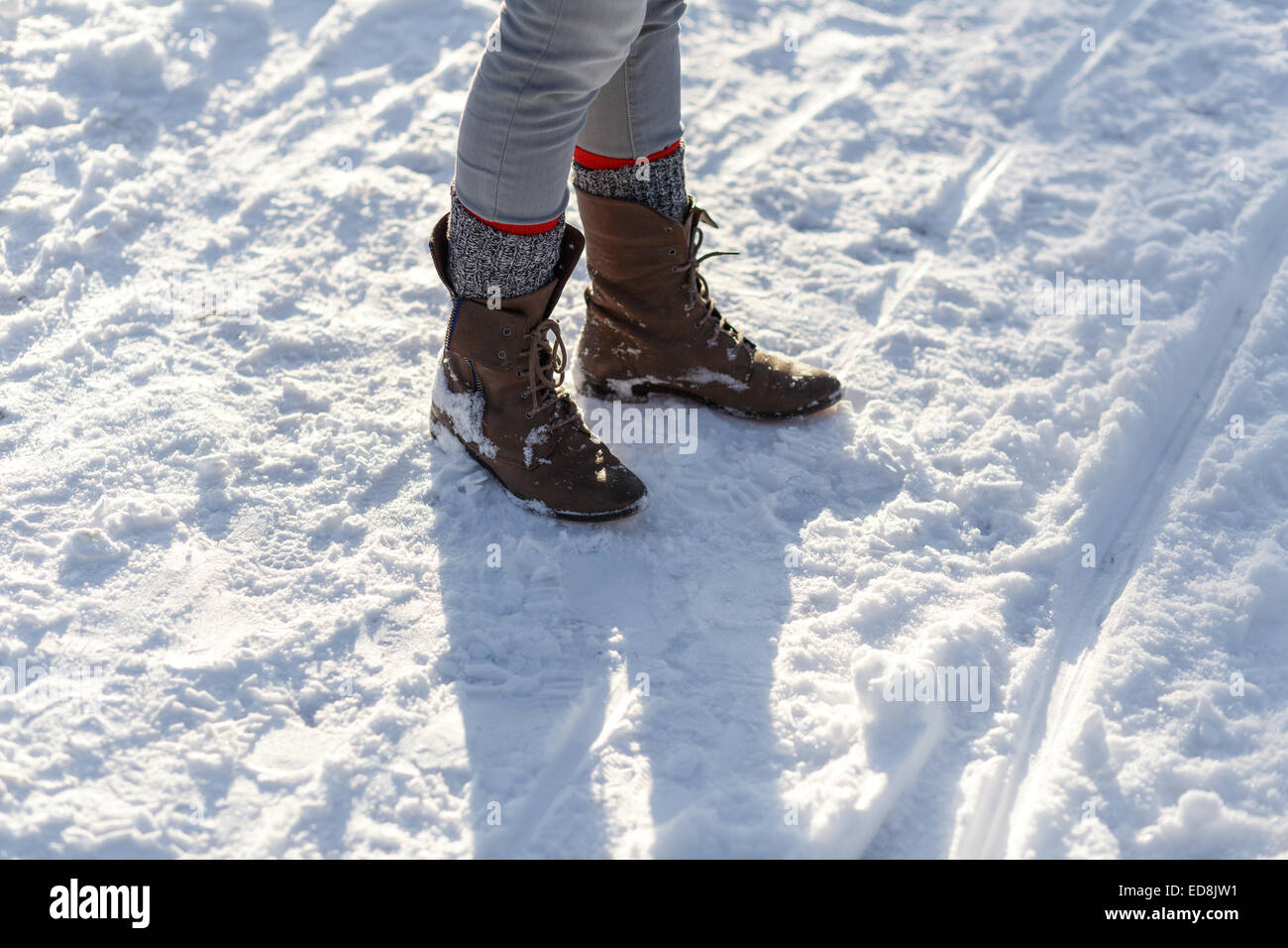 Las piernas de chica delgada en botas de luz en la nieve del invierno. Foto de stock