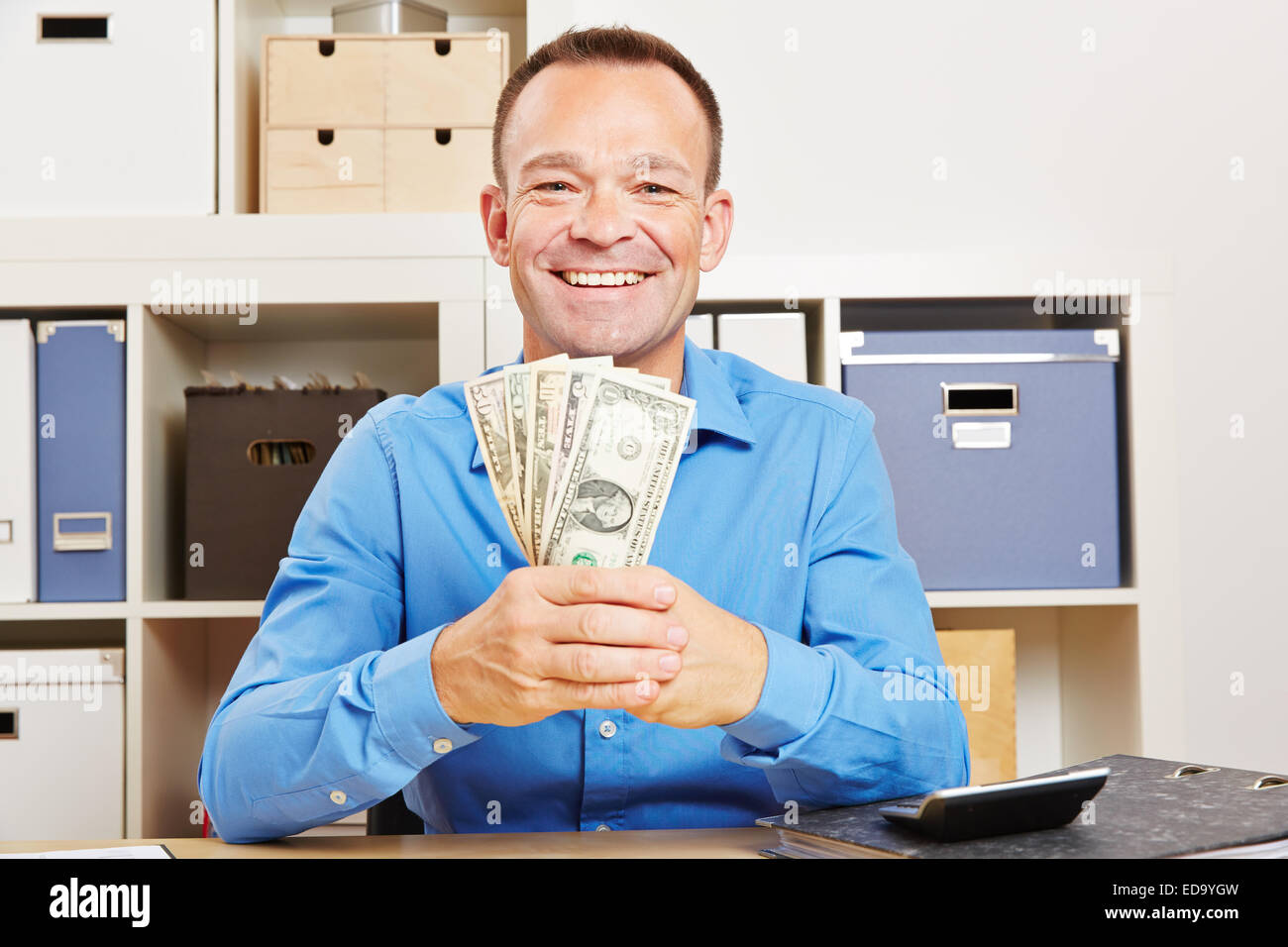 El hombre de negocios feliz celebración fan de dollar dinero facturas en su escritorio Foto de stock