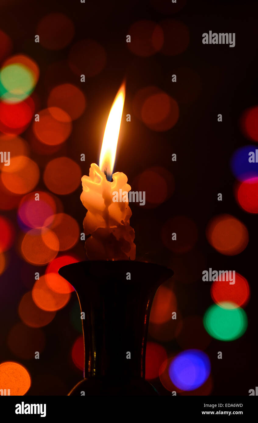 Una vela encendida con un suave fondo abstracto de las luces de Navidad Foto de stock