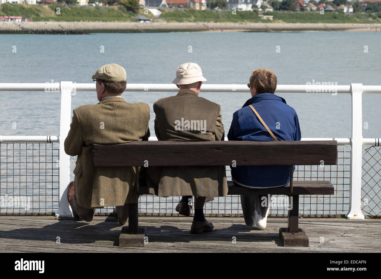 Tres ancianos sentados junto al mar en Clacton-on-Sea a Inglaterra Foto de stock