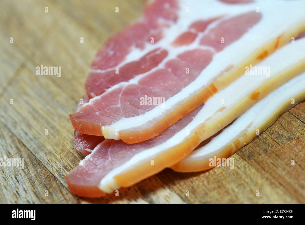 Sin cocer el tocino sobre una tabla de cortar Foto de stock