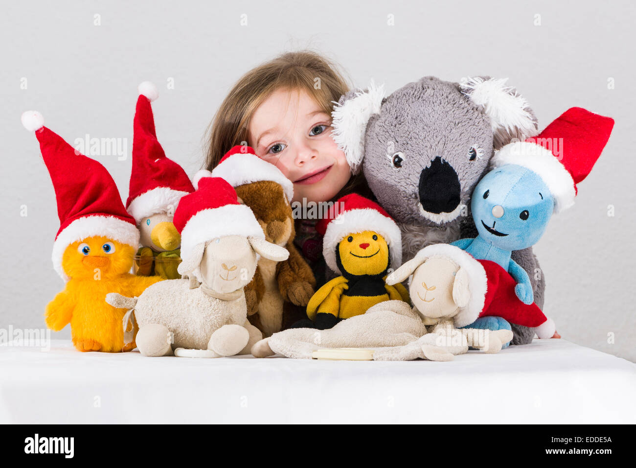 Niña de 3 años, con juguetes de peluche luciendo gorros de Santa Claus Foto de stock