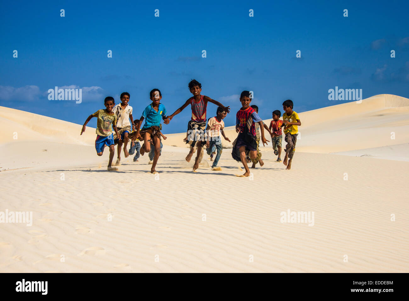 Jóvenes muchachos Socotrian girando en las dunas de arena en la costa sur de la isla de Socotra, Yemen Foto de stock